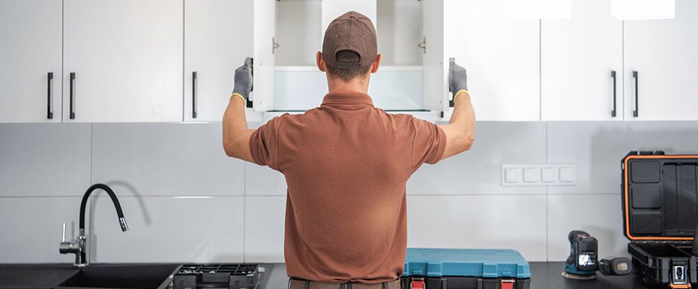 Handwerker prüft Funktion der Küchenschranktüren